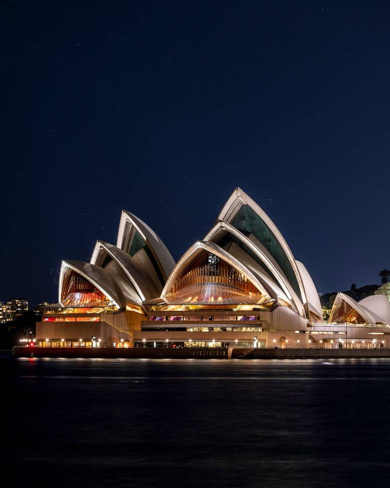 The Sydney Opera House lit up against the harbour at night, Australia
