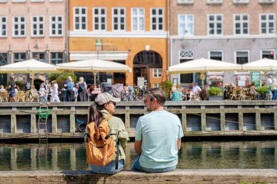 A couple by the colourful waterfront houses of Nyhavn, Copenhagen, Denmark