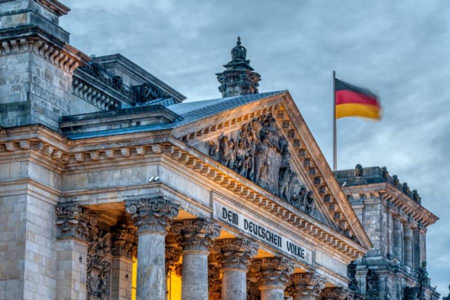 The Reichstag building with its DEM DEUTSCHEN VOLKE inscription and the German flag, Berlin, Germany