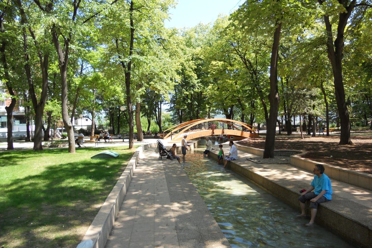The leafy spa park of Niška Banja, with a small arched bridge over a thermal-water channel where visitors cool their feet.