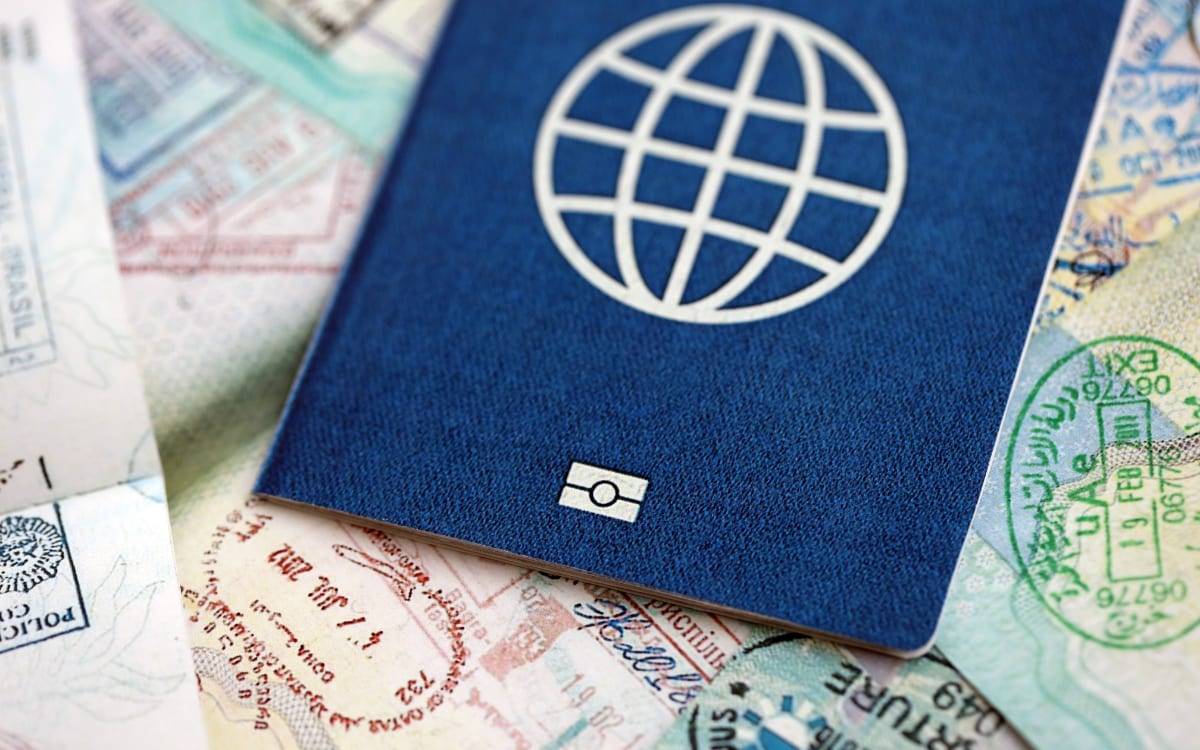 A blue biometric passport with a globe emblem resting on pages full of entry and exit stamps