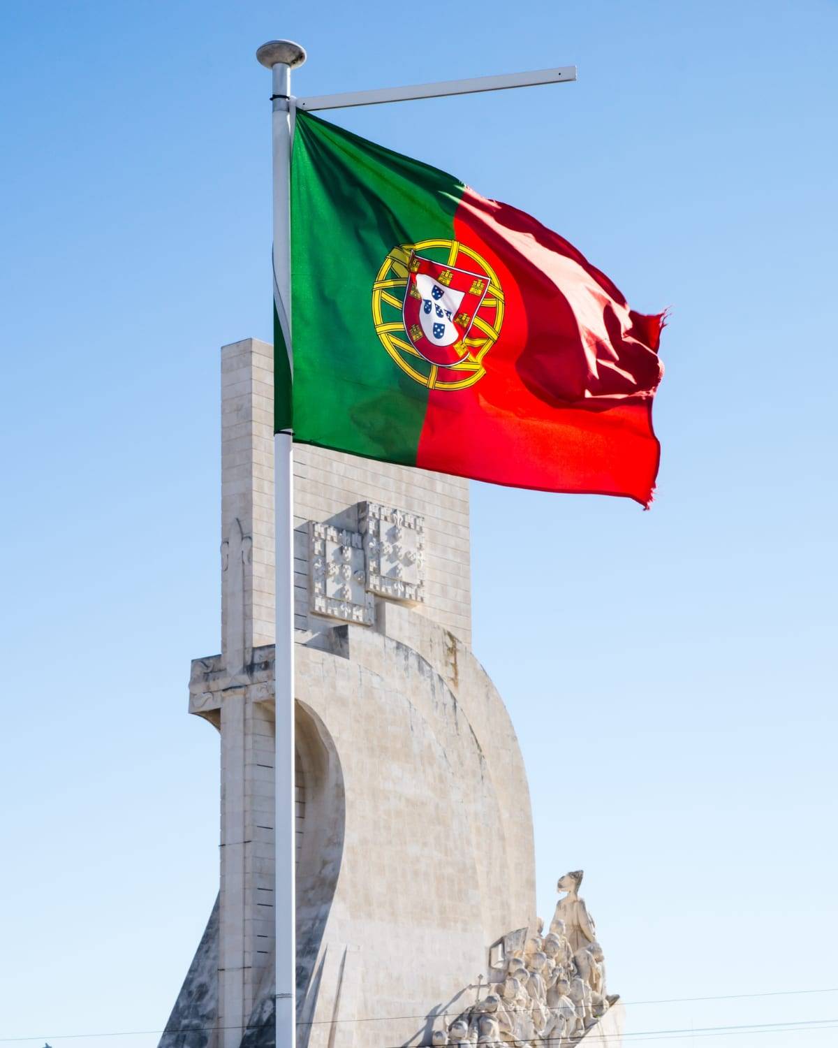 The Portuguese flag flying over the Monument to the Discoveries in Lisbon, Portugal