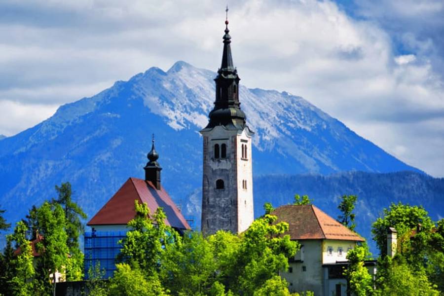 A church spire below the snow-capped Karavanke mountains near Lake Bled, Slovenia