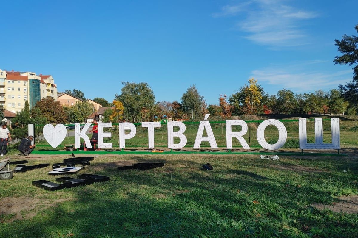 Store hvite 'Kertváros'-bokstaver i en grønn park foran boligblokker i bydelen Ker i Subotica.