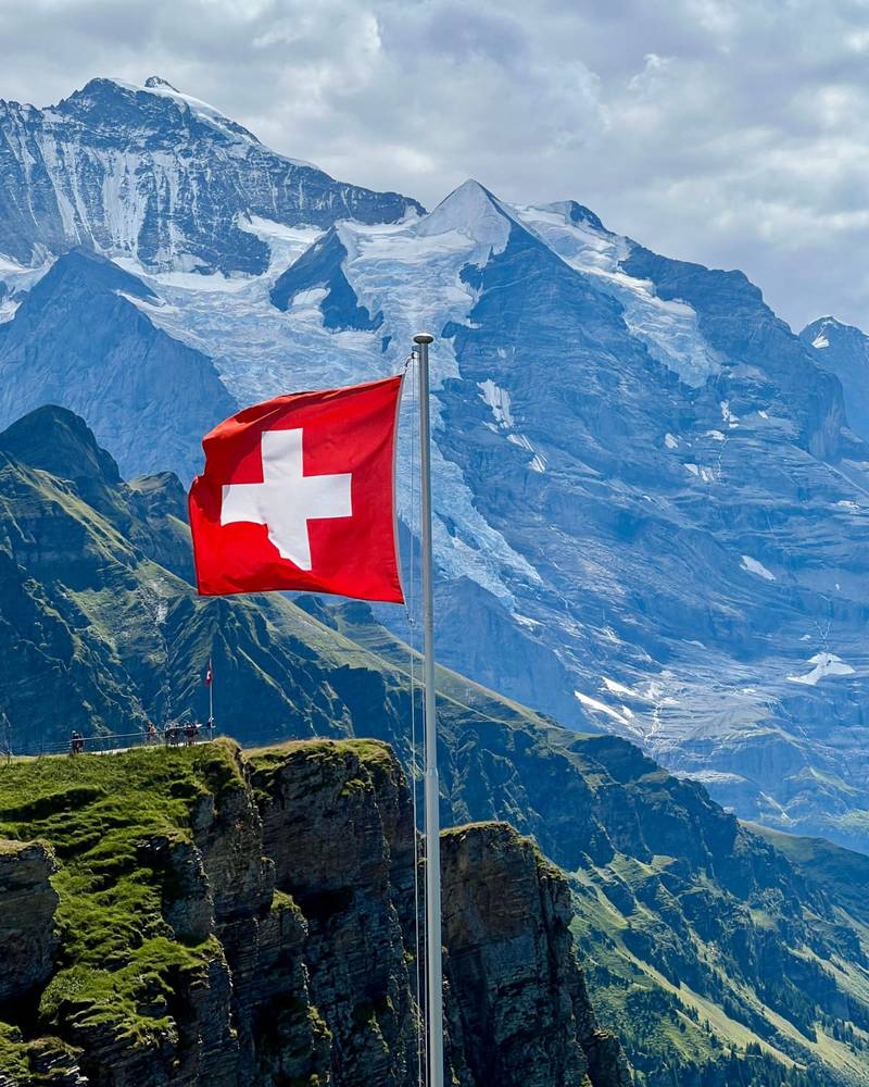 Den schweiziska flaggan ovanför Berner Alperna nära Jungfrau, Schweiz