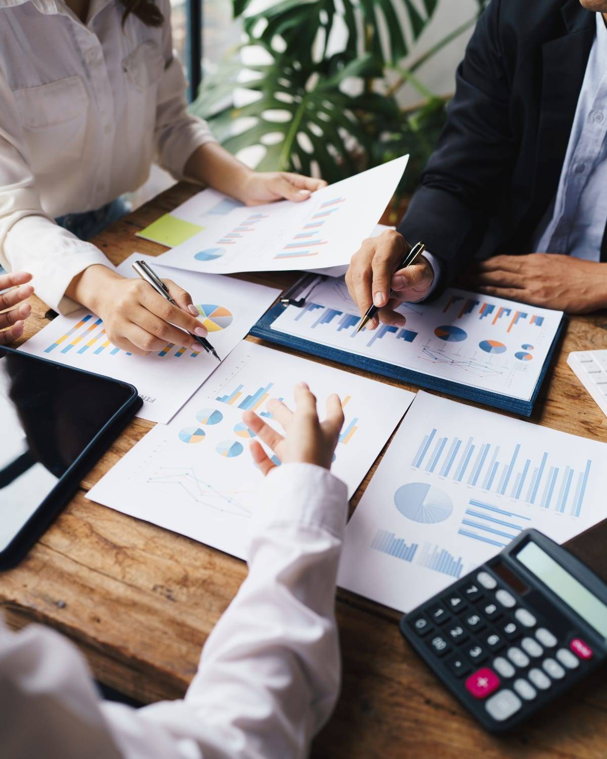 Two advisors reviewing financial charts and graphs with pens and a calculator