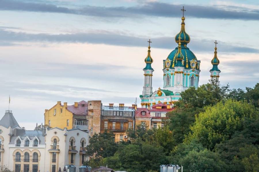 The green and gold domes of St. Andrew's Church above the rooftops of Kyiv, Ukraine