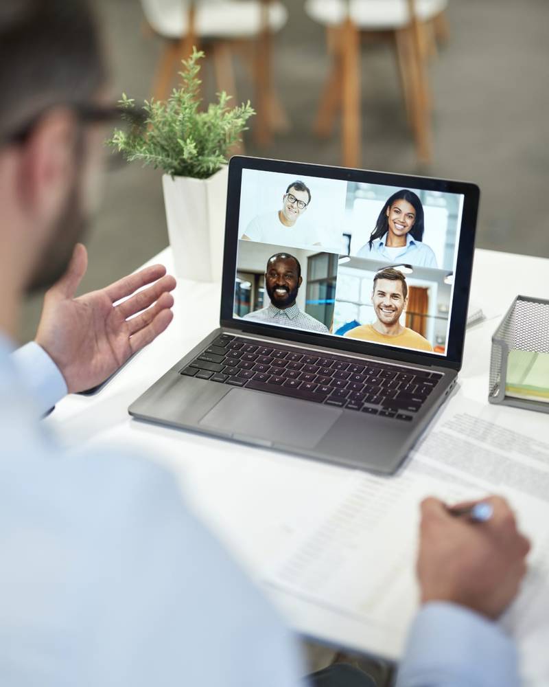A person on a laptop video call with four remote team members on screen